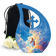 Decorative urn with angel design, cross, and roses on a white background