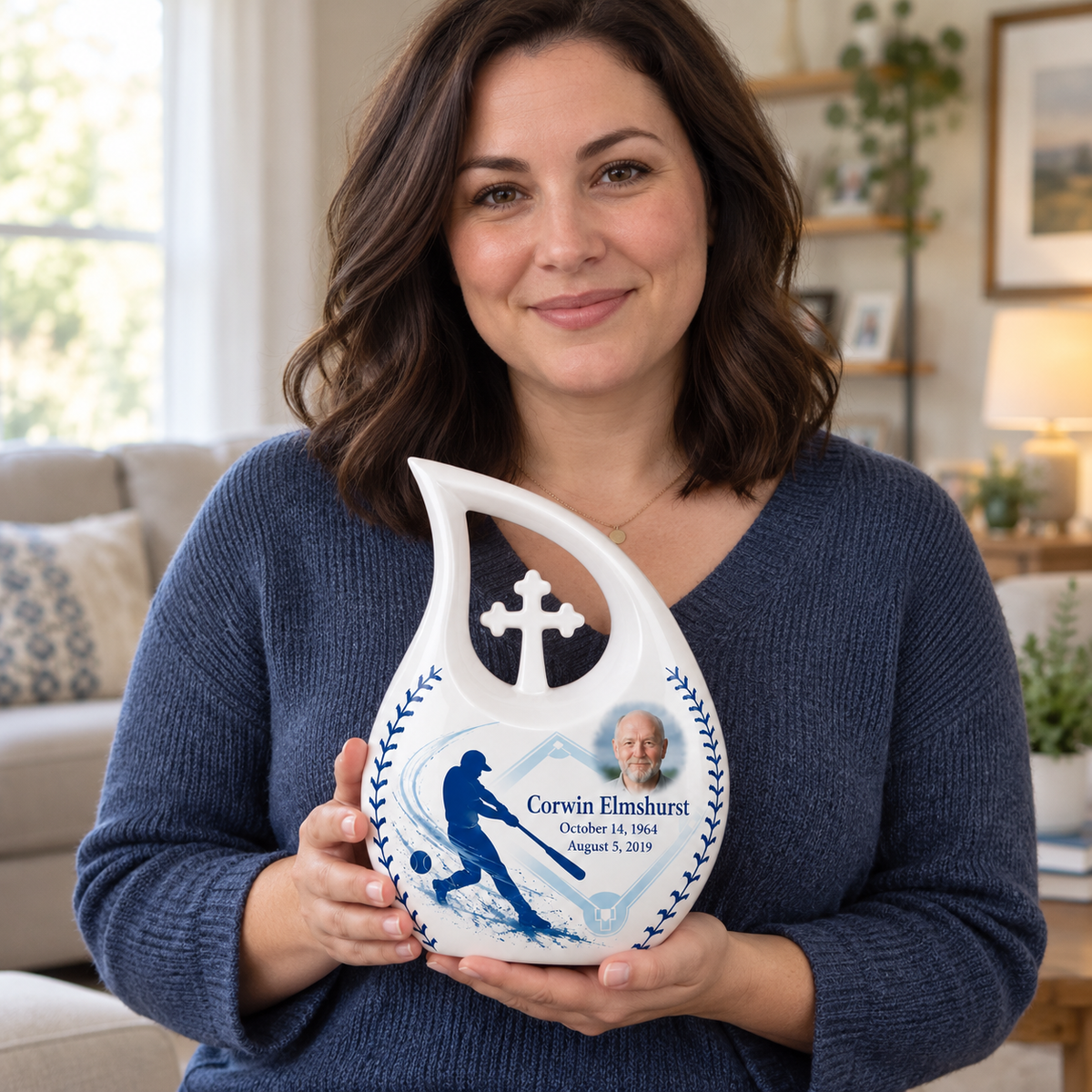 An adult holding the Cross Drop baseball memorial urn, with its personalized artwork visible.