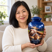 An adult holding the Classic baseball memorial urn, with its personalized artwork visible.