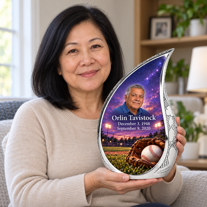 An adult holding the Curved Drop baseball memorial urn, with its personalized artwork visible.