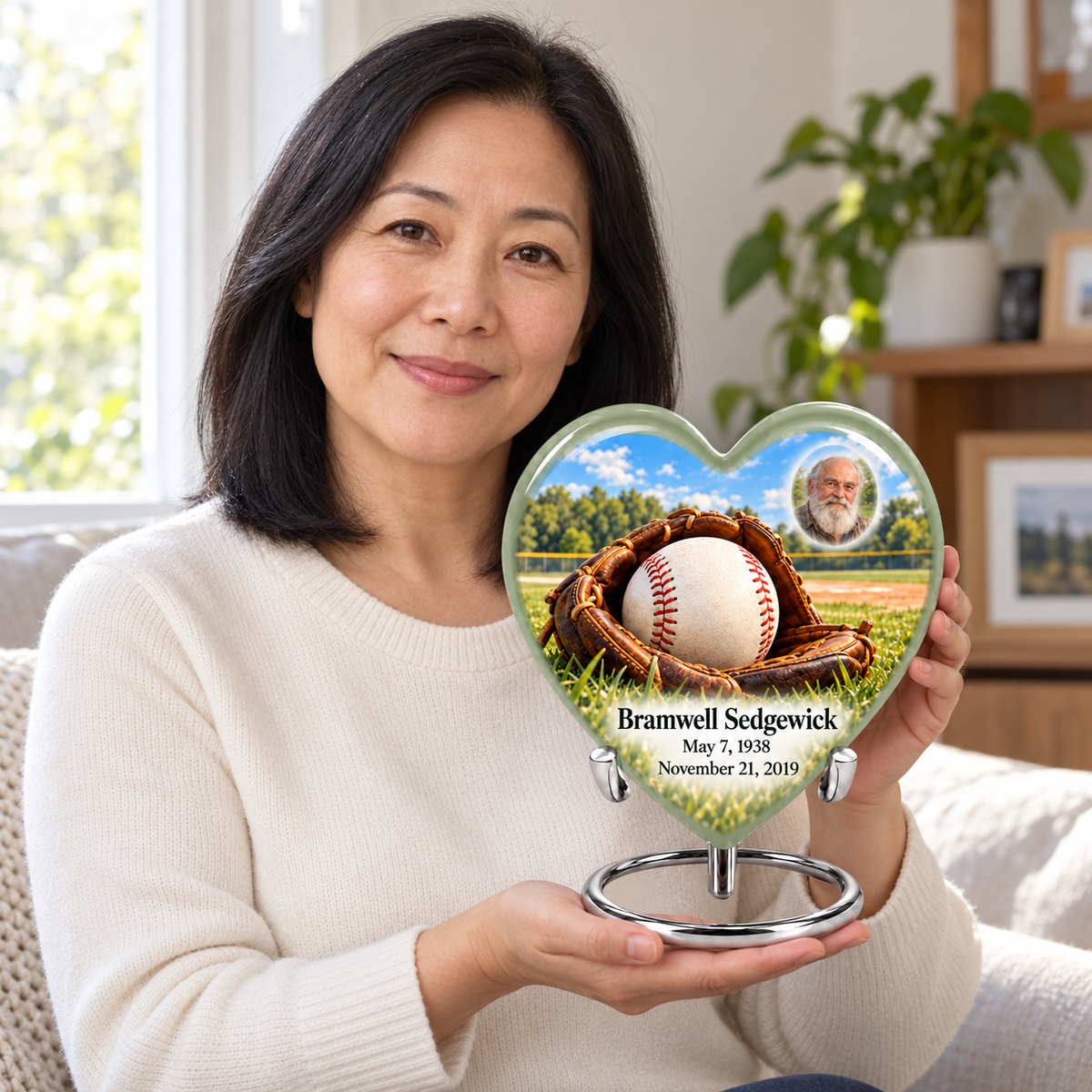 An adult holding the Heart baseball memorial urn, with its personalized artwork visible.
