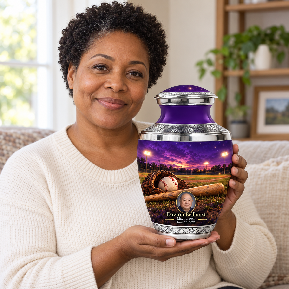 An adult holding the Tasty baseball memorial urn, with its personalized artwork visible.