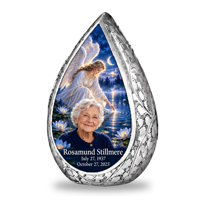 1 Keepsake 3 inch Urn Straight Drop memorial urn, angel beside quiet blue water, Rosamund Stillmere portrait and full memorial dates, white background.