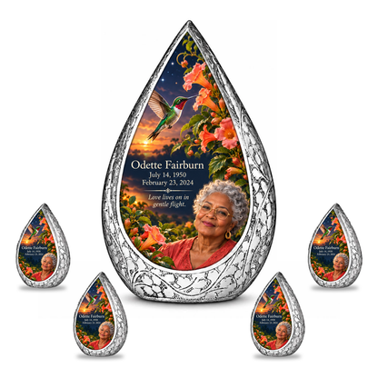 Hummingbird 01 Straight Drop, 10 inch large Urn with 4 Keepsake 3 Inch Urns: original engraved silver frame surrounding a ruby-throated hummingbird, peach-coral trumpet vine and apricot-to-navy dusk; fictional Odette Fairburn portrait, name and full dates.
