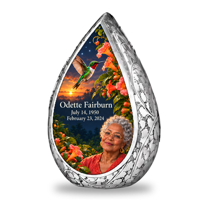 Hummingbird 01 Straight Drop, 1 Keepsake 3 inch Urn: original engraved silver frame surrounding a ruby-throated hummingbird, peach-coral trumpet vine and apricot-to-navy dusk; fictional Odette Fairburn portrait, name and full dates.