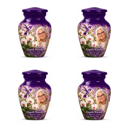 Four identical 3-inch keepsakes in the Classic urn with violet hummingbird above white orchids, fictional Elspeth Waverly portrait with silver braid and violet glasses, name and full memorial dates on white.