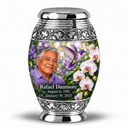 One 3-inch Monar keepsake with low silver cap, grooved neck and silver scroll bands, violet hummingbird, white orchids and fictional Rafael Dunmore memorial portrait and dates.
