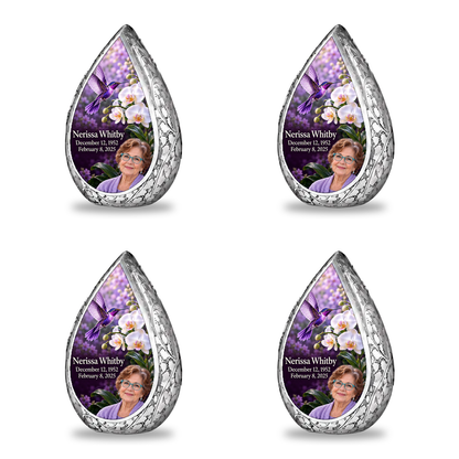 Four matching silver Straight Drop keepsakes arranged in two rows, each with violet hummingbird, white orchids and Nerissa Whitby portrait, name and full dates.