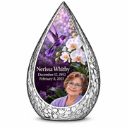 Large silver Straight Drop memorial urn with a violet hummingbird above white orchids on a plum background and Nerissa Whitby portrait, name and full dates.