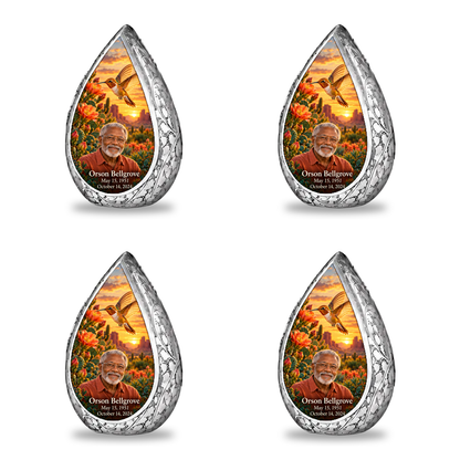 Four matching keepsakes Straight Drop memorial urn, golden hummingbird at orange desert cactus blooms, Orson Bellgrove portrait and full memorial dates, white background.