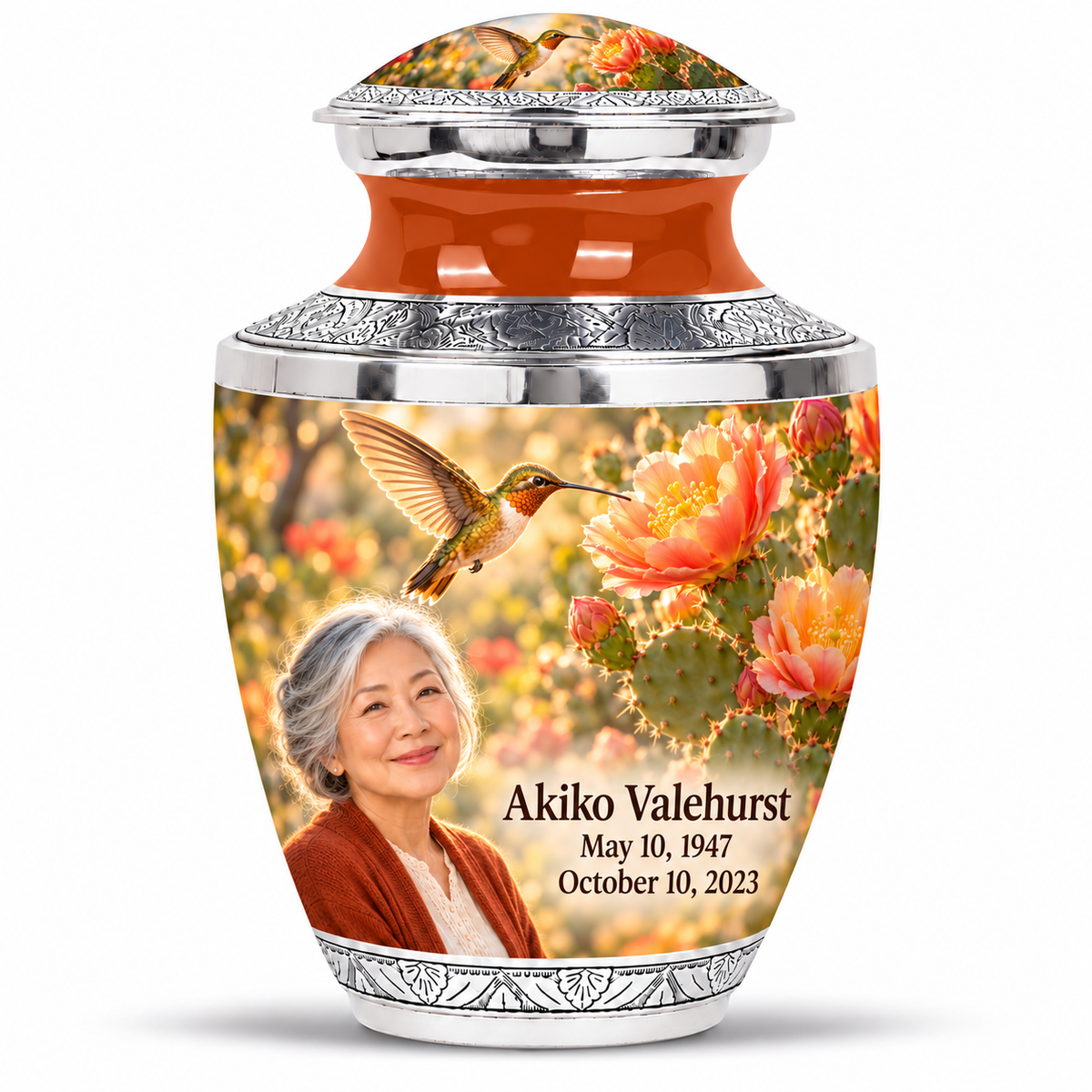 One large Tasty urn with domed artwork lid, orange neck, silver trim, golden hummingbird over cactus flowers and fictional Akiko Valehurst portrait, May 10, 1947 to October 10, 2023.