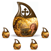 One 10-inch large urn with four matching 3-inch keepsakes, Cross Drop golden-ginkgo woodland-path design with fictional Vera Ashcombe portrait, name and full memorial dates on white background.